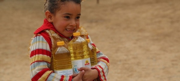 WFP/Abeer Etefa Une petite syrienne porte des bouteilles d'huile fournies par le PAM. Photo: PAM/Abeer Etefa